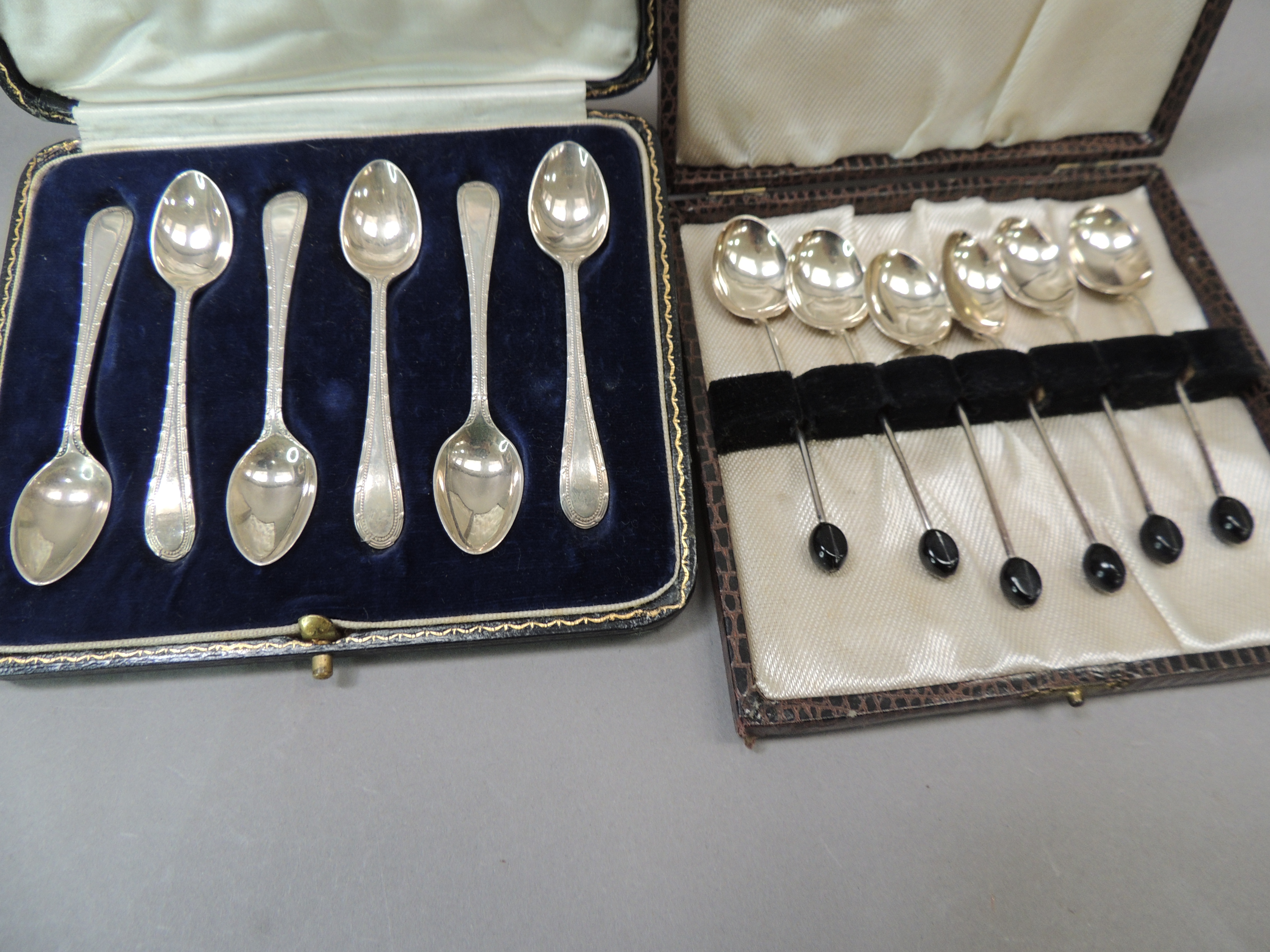 A cased set of silver tea spoons together with a set of silver coffee spoons with black coffee