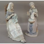 A pair of Lladro porcelain figures of seated females both sewing, 28cm high approximately