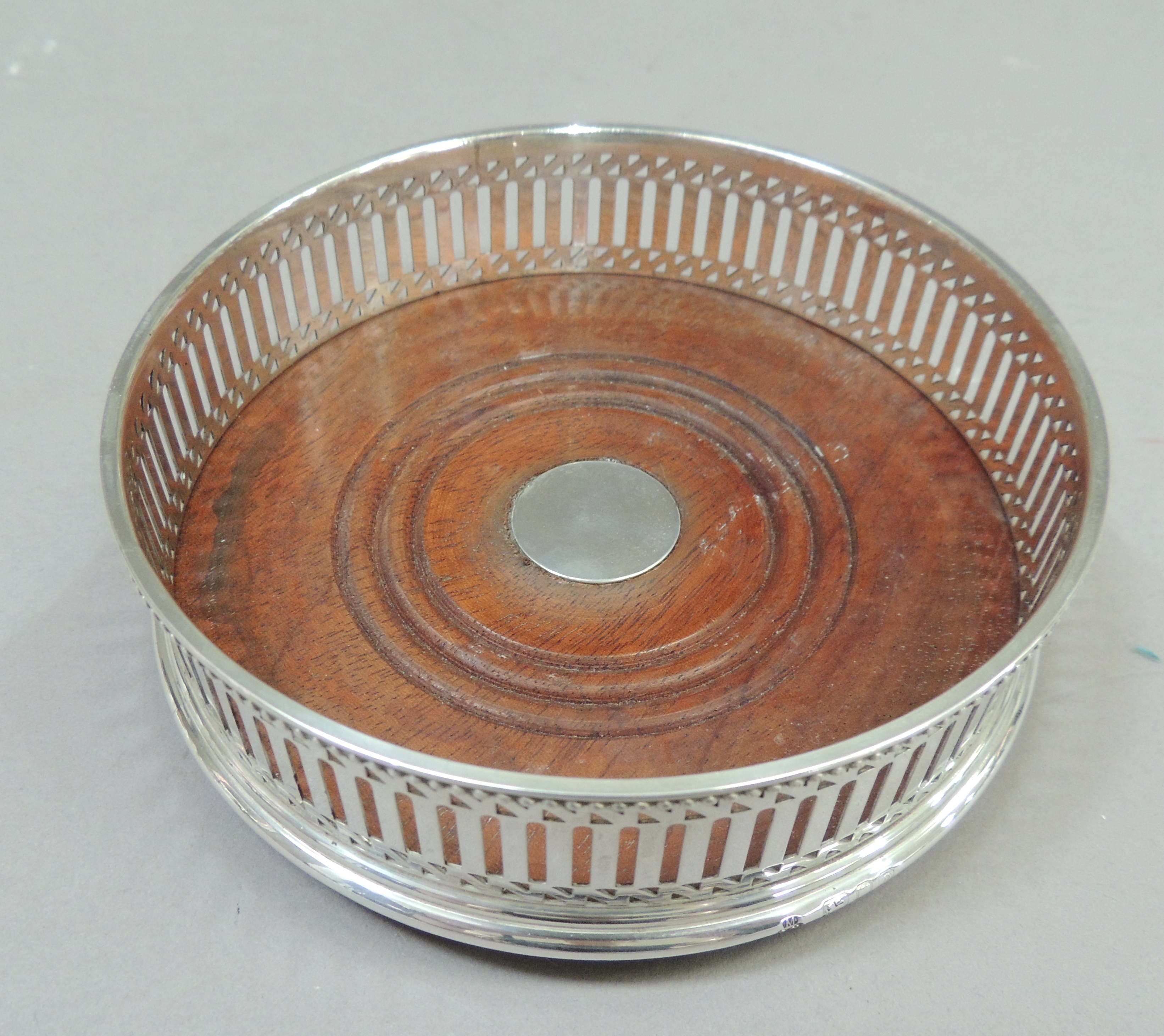 A George III style silver bottle coaster with beaded rim above a pierced band, draught turned wooden