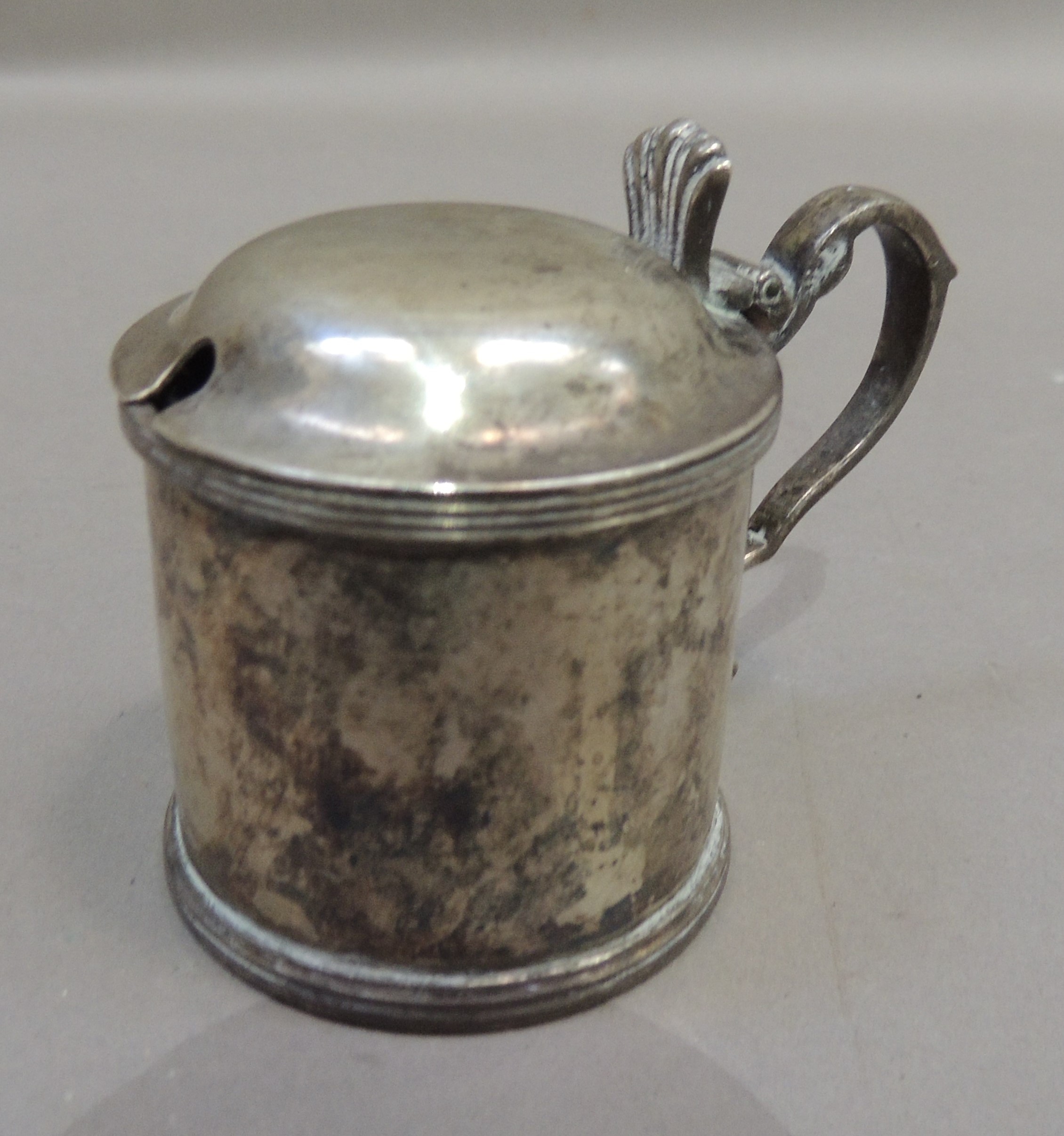 A George V silver lidded mustard with fluted thumb piece and reeded bands, scroll handle, 6cm high