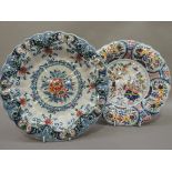 Two Makkum faience dishes, circular with fluted rims, the first painted with urns of flowers to