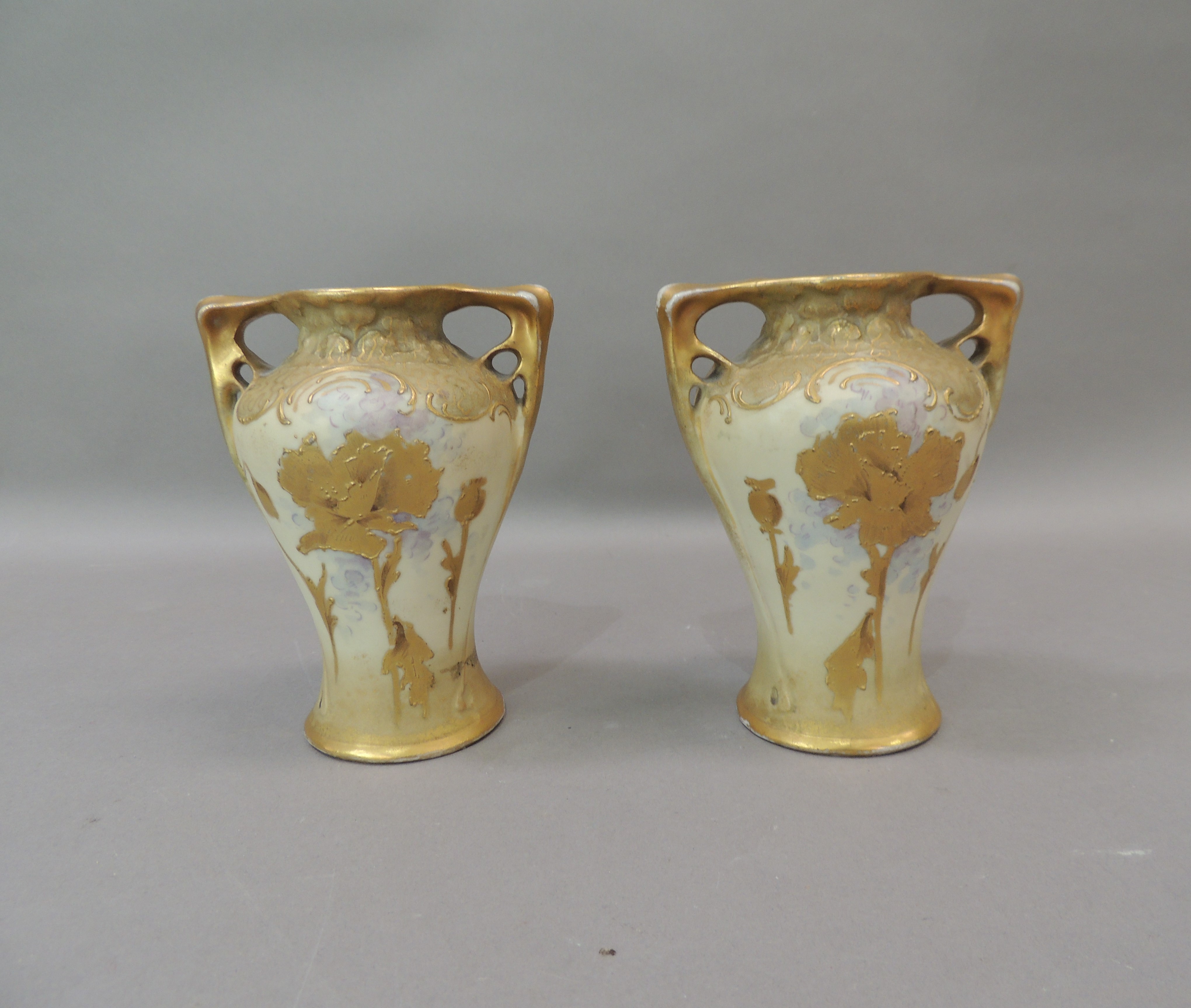 A pair of Amphora two handled vases gilt with poppies and other flowers, 14cm