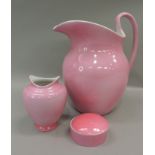 An early 20th century pink glazed toilet jug, vase, soap dish and cover