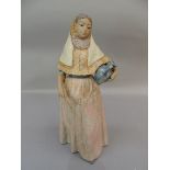 A lladro figure of a young Spanish girl holding a picture beneath her left arm, a fan in her right