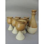 A set of six studio pottery goblets and matching decanter, the glazed tulip shaped tops on buff