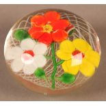 A glass paperweight with white, yellow and orange flowers on a white latticino ground, ground