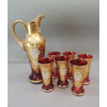 A Venetian style ruby glass carafe and six beakers decorated in gilt and heavy enamels with floral