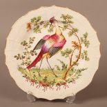 A Creamware plate painted in the style of Chelsea with an exotic bird and tree in polychrome