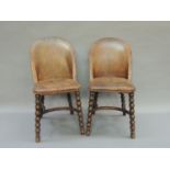 A pair of tan leather and close nailed single chairs, the tub shape back embossed with a shield