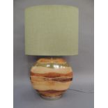 A wood effect strata table lamp of flattened moon shape on a metal base, complete with pale green