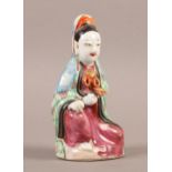A CHINESE PORCELAIN FAMILLE ROSE FIGURE of a kneeling female with pink robe and green and blue
