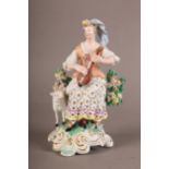 AN 18TH CENTURY DERBY PORCELAIN FIGURE OF A SHEPHERDESS playing a mandolin, a sheep beside her, with