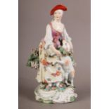 AN 18TH CENTURY PORCELAIN FIGURE OF A SHEPHERDESS AND SHEEP with bocage painted in polychrome