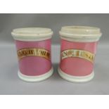 A pair of 19th century pottery pharmacy jars, glazed in pink, lettered in gilt and black, with