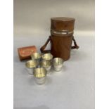 A set of three glass and white metal spirit flasks held in a leather drum case initialled MAB