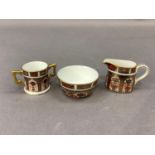 A Royal Crown Derby miniature sugar bowl and cream jug and a two handled loving cup all in pattern