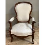A Victorian walnut nursing chair with moulded waisted back, scrolling arms and legs, stuffed over
