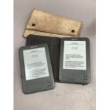 Two Amazon Kindles without chargers together with a snakeskin bag