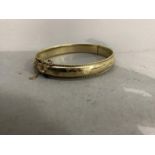 A stiff hinged bangle in 9ct gold, foliate engraved within a twisted wire edge, approximate width