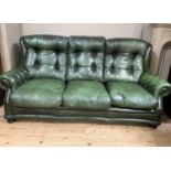 A three piece buttoned green leather lounge suite with close studded detail on bun feet