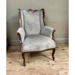 A late Victorian or Edwardian mahogany framed arm chair upholstered in grey dralon, the shaped top