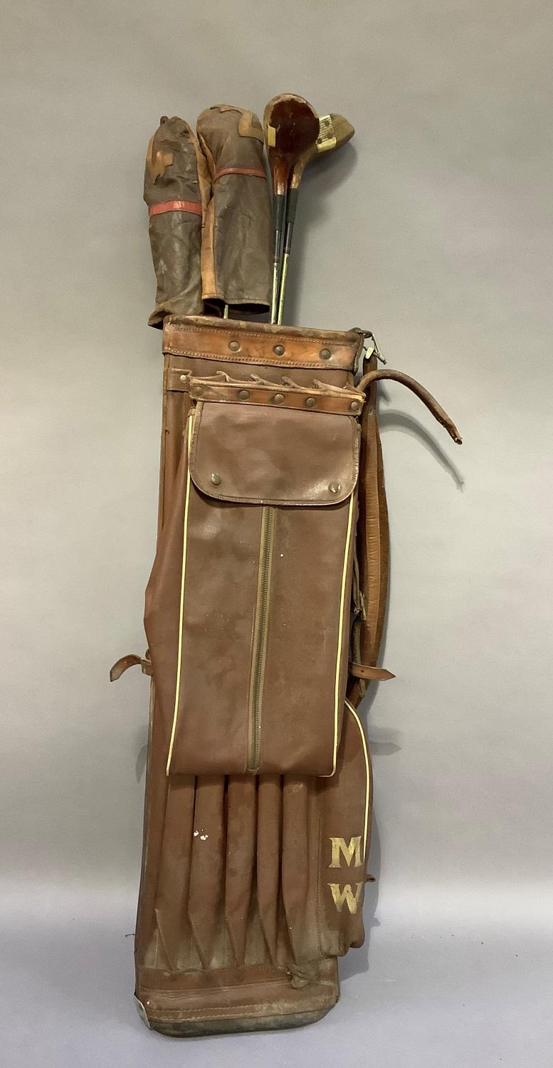 A vintage golf bag together with vintage clubs by Gradidge including drivers, two with leather