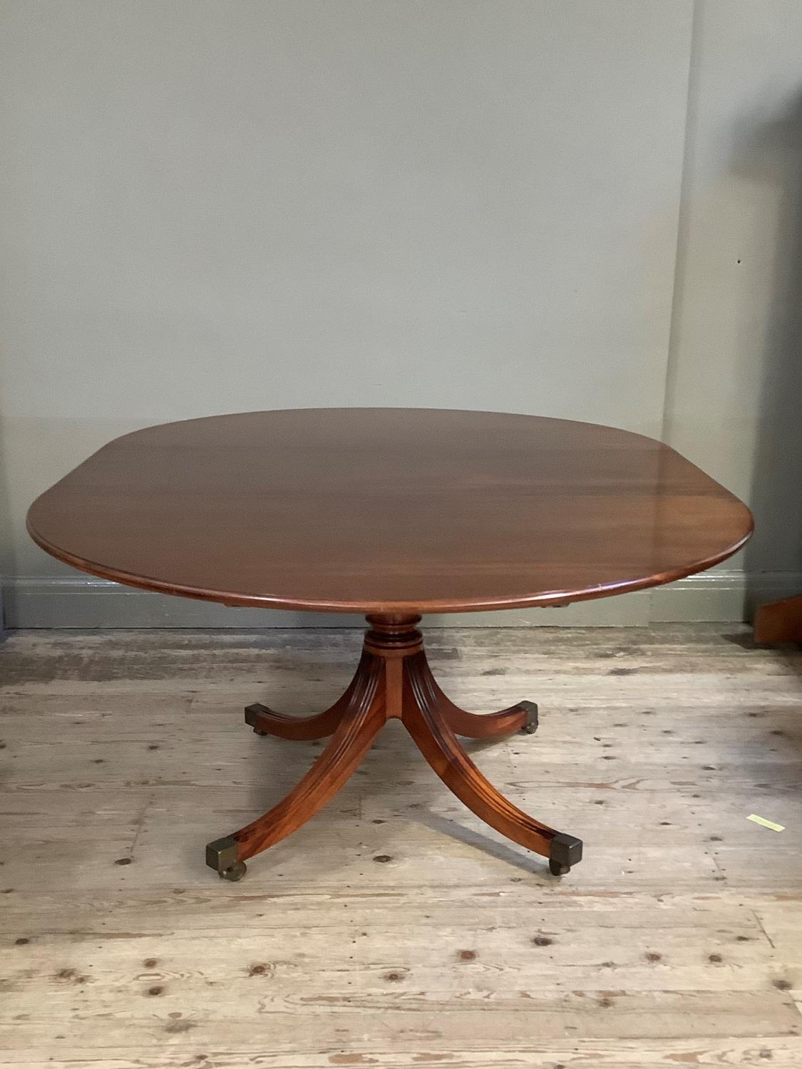 A reproduction mahogany Regency style dining table, the oval top above a gun barrel column and