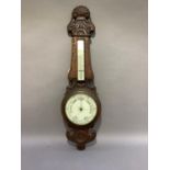 A late Victorian oak framed aneroid barometer with thermometer, foliate and shell carved case,