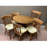 A circular pine kitchen table together with a set of five rail back pine kitchen chairs including an