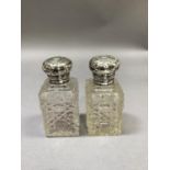 A pair of George V cut glass scent bottles with silver collars and hinged bun shaped covers embossed