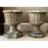 A pair of concrete garden vases of fluted cylindrical form on waisted bases and octagonal plinths,
