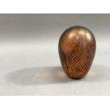 An iridescent glass paperweight, the amber mottled ground with swirled pattern, 11.5cm