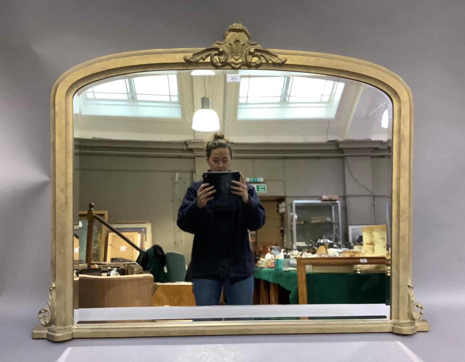 A reproduction gilt over mantel mirror in Victorian style with central foliate applied detail,