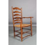 An early 19th century oak ladder back elbow chair, shaped arms on baluster supports, turned legs