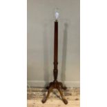 A reproduction mahogany standard lamp with fluted column, foliate carved at the base on four