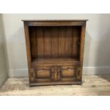 A reproduction oak bookcase, adjustable shelved interior above pair of arched raised fielded panel