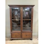 An oak bookcase with flared cornice enclosed by a pair of lead glazed doors, the base fitted two