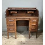An oak tambour topped twin pedestal desk with interior of pigeon holes and drawers, arched