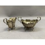 A silver two handled sugar bowl and matching cream jug of panelled form with C-scroll rim and leaf