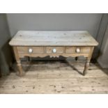A Victorian stripped pine side table, the rounded rectangular top above three short drawers,
