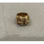 A double buckle ring in 9ct gold set with cubic zirconia raised against a scrolled shank, size