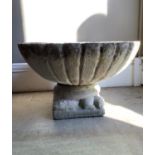 A concrete circular fluted garden planter on lizard base with square plinth, 69cm diameter