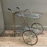 A vintage lacquered glass tubular framed two tier drinks cart with glazed shelves and 'wagon