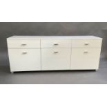 A white lacquered sideboard, the rectangular top above three short drawers and three cupboards,