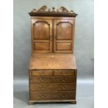 An oak bureau book case, flared cornice, arched fielded panelled doors flanking central fluted