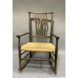 An oak framed rocking chair, the top rail above pierced rail splat, rush seat, turned leg joined