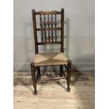 A reproduction stained ash and rush seated spindle back chair on turned legs with bun feet