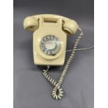A cream plastic wall mounted telephone and hand piece