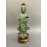 A soapstone figure of Guanyin standing on a lappet carved, waisted and rounded rectangular base,