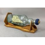 A model ship in a bottle on a wooden stand, overall length with stand 32cm